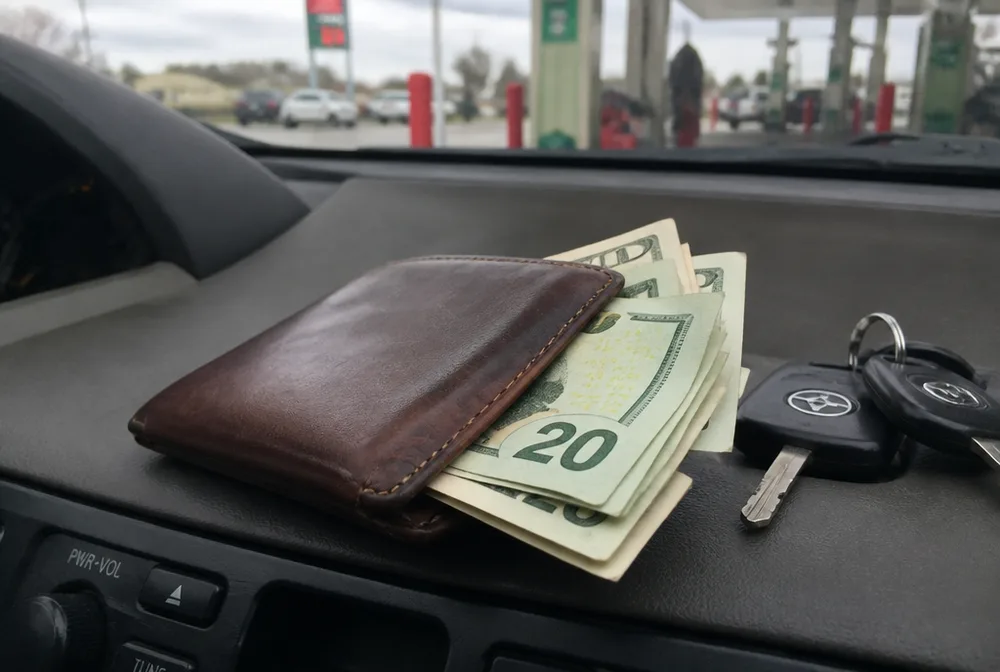 Wallet and car keys on a dashboard at a gas station